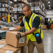 Warehouse worker handling labeled cartons while wearing an Agoz shoulder sling case with an Almex mobile computer for hands-free fulfillment workflows.