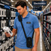 Retail associate wearing a black AGOZ crossbody scanner case with a Datalogic mobile computer while checking a product in an electronics aisle.
