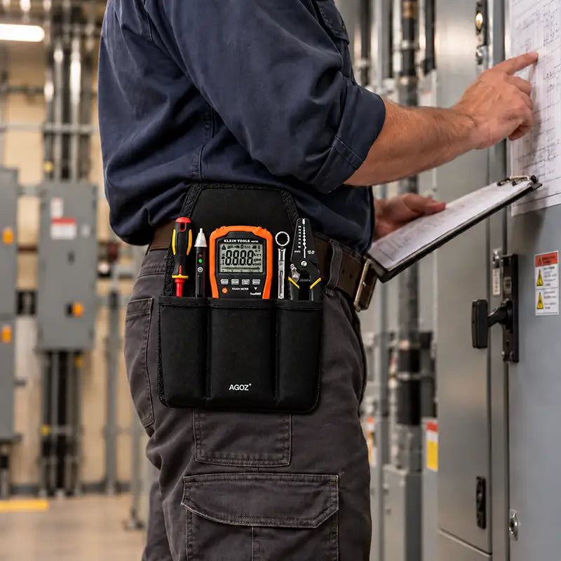 Side view of industrial electrician wearing an Agoz utility tool pouch with Klein Tools multimeter and hand tools while reviewing electrical inspection documents.