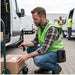 Field service worker scanning a package with a Unitech trigger scanner while wearing an Agoz holster at a delivery vehicle.