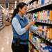 Retail associate using a Newland handheld scanner for shelf inventory while wearing an Agoz belt holster in a store aisle.