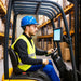 Warehouse forklift operator using a rugged tablet mounted beside the steering controls with an AgozTech holder.
